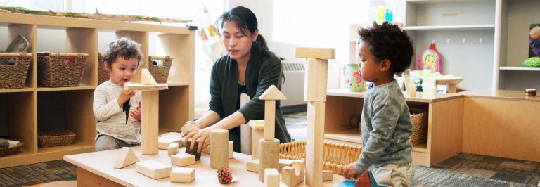 children and child care professional playing with building blocks